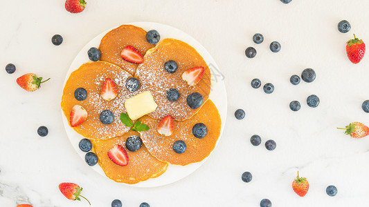 健康早餐煎饼蓝莓和草莓水果放在石桌图片