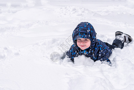 一个小孩从雪地或冰块中向外张望一个孩子在玩雪躺在雪地里微图片