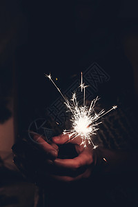 手拿着燃烧的烟花孟加拉灯文本的空间在黑暗中在女手中燃烧火花特写新年快乐和圣诞快乐的概念节背景图片