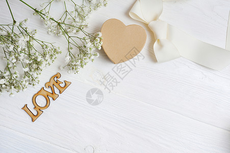 样机花组成的白色礼物满天星与一颗心和白色木制背景上的铭文爱情人节平躺图片