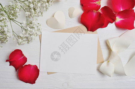 样机花组成从满天星与一个心字母与白色木制背景上的红色玫瑰花瓣情人节平躺背景图片