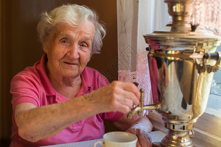 年长妇女在餐桌上喝茶古图片