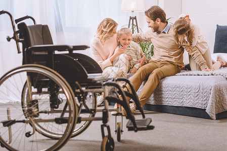 患有残疾的父亲和母亲与子女一起在床上图片