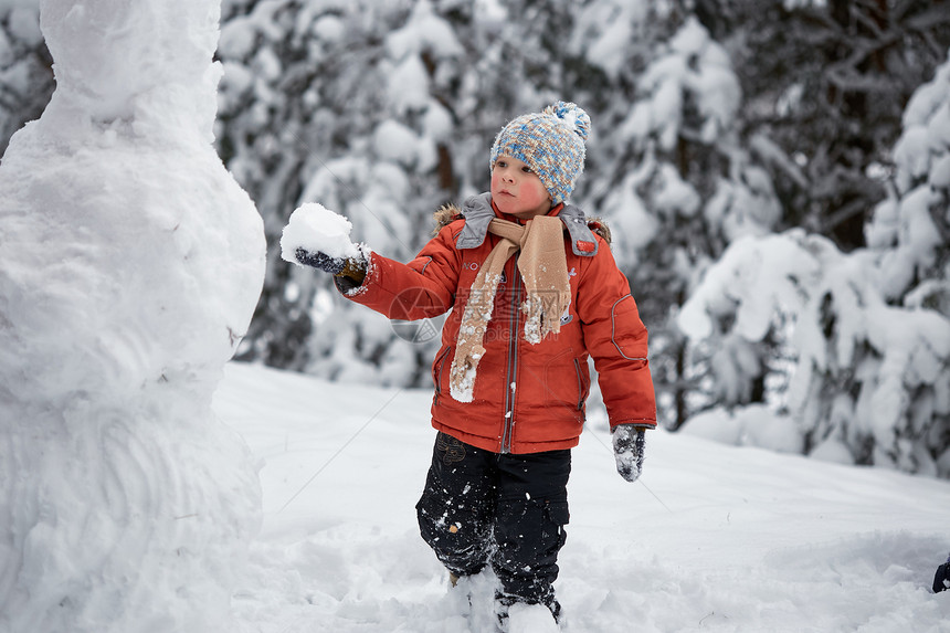 冬天的乐趣男孩雕刻雪人图片