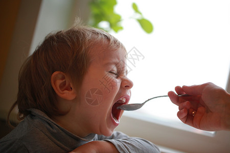 孩子坐在桌边用勺子吃酸奶图片