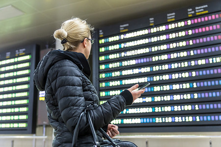 国际机场的休闲女人看着航班信息板图片