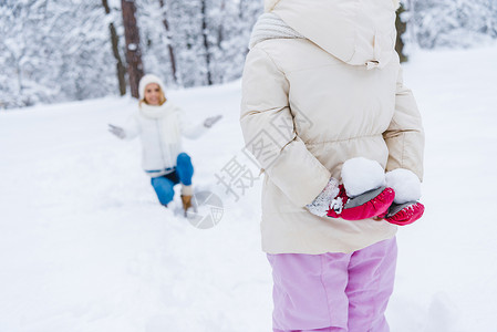 女儿带着雪球和幸福的母亲在冬季公园跪在地上时图片