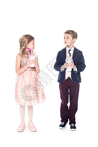 可爱时装可爱的小孩在塑料杯中握着奶昔彼此在白边图片