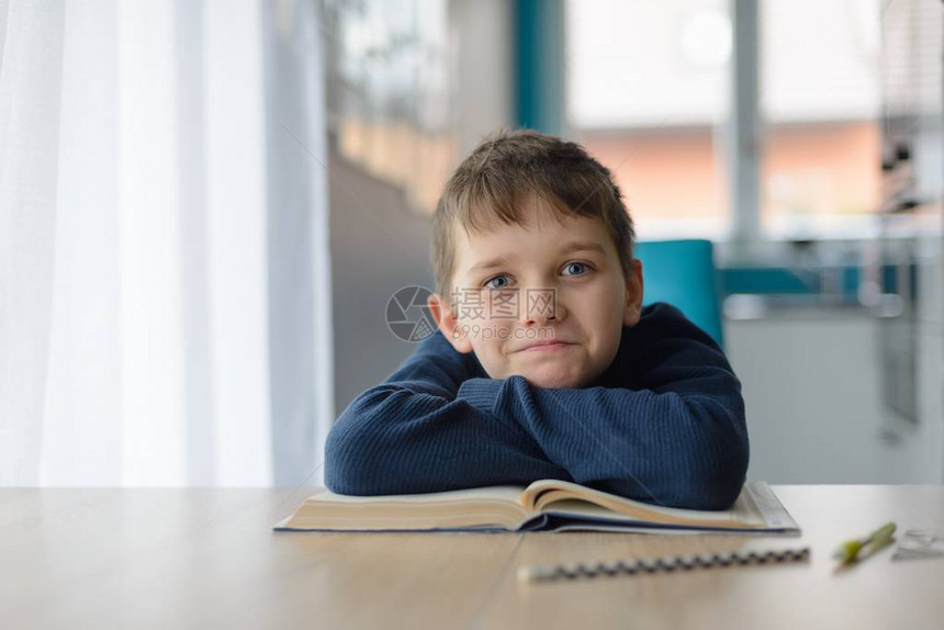8岁快乐的男孩在桌子上做功课图片