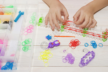 女孩手用橡皮筋制成的腕带和戒指彩虹织机编织图片