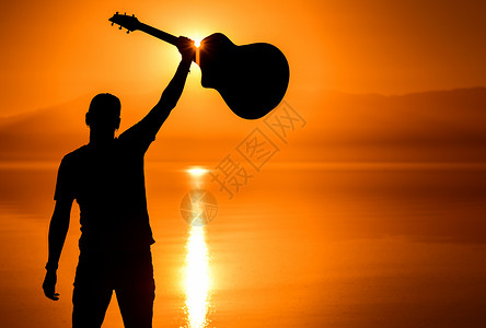 成功的吉他玩家和景色日落成年男音乐家图片