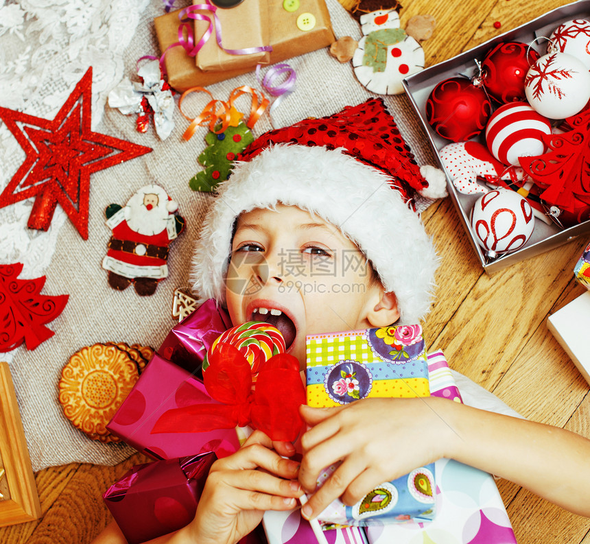可爱的小男孩在家里有圣诞礼物在圣诞老人红帽微笑的盒子上关图片
