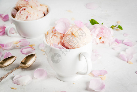 夏季清新甜点食用织物食品含玫瑰花瓣和杏仁的冰淇淋白服务碗白混凝土图片