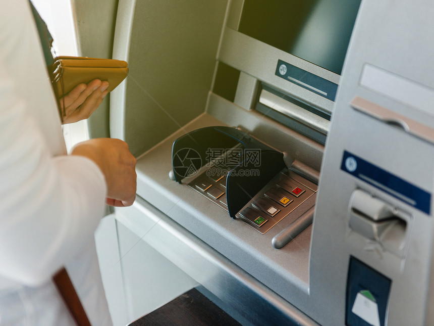 使用ATM持有钱包并在键盘自动柜员机上按PIN安全号码图片