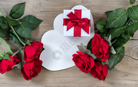白色礼物盒周围的红玫瑰红色玫瑰以平面观图片