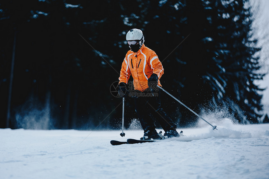 山坡上的男滑雪者背景是冰冻的黑暗森林冬季森林山滑雪图片