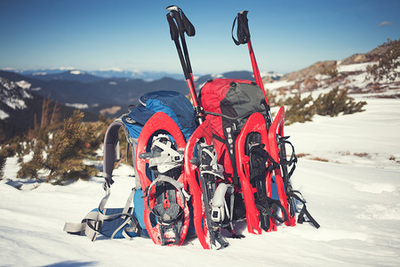蓝背包红雪鞋和滑雪杆站在雪地上图片