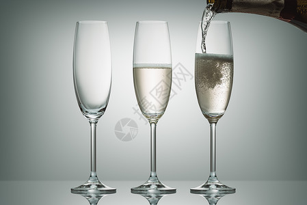 把香槟从瓶子里倒进三个白色的杯子里图片