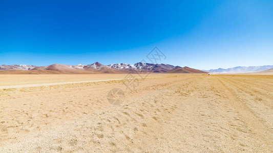 高海拔的土路与安第斯高地的沙质漠和贫瘠的火山范围前往玻利维亚著名的乌尤尼盐背景图片