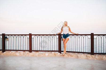 可爱快乐的女孩在度假村享受暑假身穿白衬衫的快乐年轻女子站在海面背景的图片