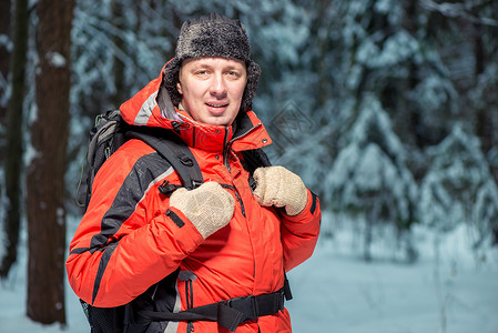在冬季森林里带着背包穿着夹克徒步旅行的快图片