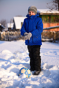 一个穿着冬装的男孩在雪上打橄榄球田里布满了深厚的雪图片