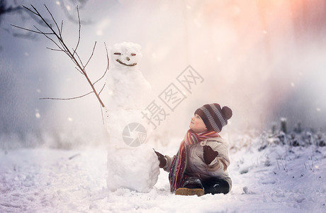 小男孩坐在冬天风景的雪人附近与雪人和小男图片