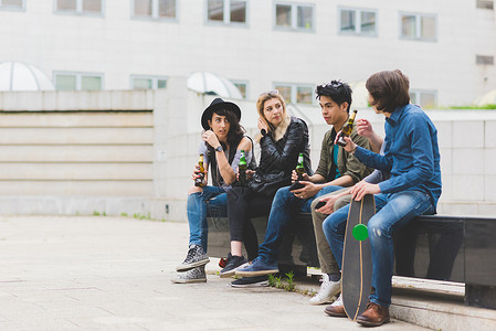 一群多民族的朋友坐在户外喝啤酒图片