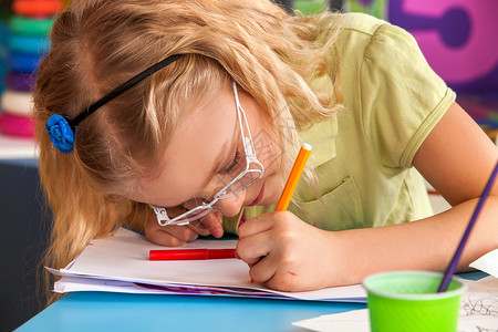 小学生在艺术学校课上画戴眼镜的孩子用桌子上的颜料画儿童近视是因背景图片