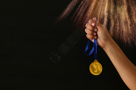 女在黑色背景和闪亮的涂层上握着金牌获图片