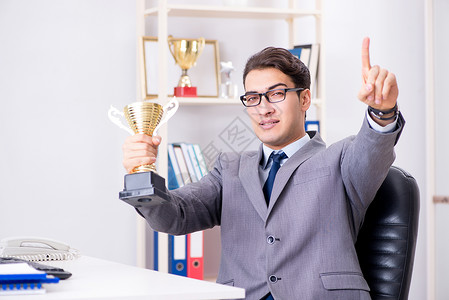 因在办公室取得成就而获得奖杯的商人图片