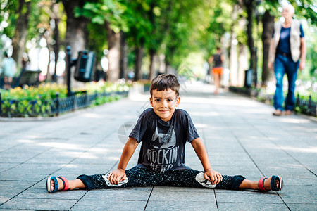 一个快乐笑容的男孩坐在公园路边的小男孩的图片