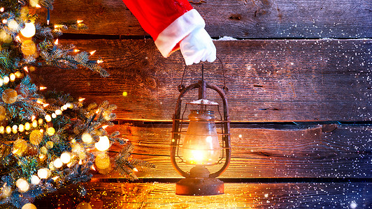 手握旧油灯的圣诞老人手架在木本面图片