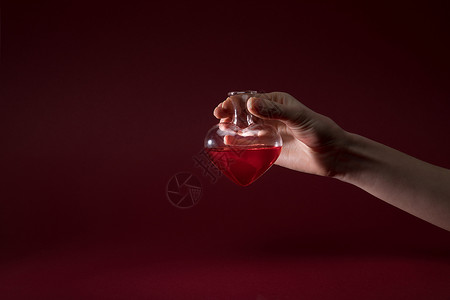 女握着心脏形状玻璃杯瓶的香水背景图片