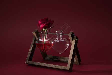 红玫瑰在心脏形状的花瓶和红色木图片