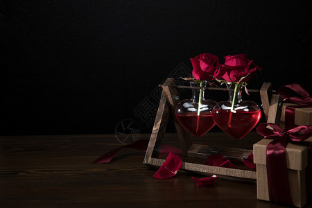 两朵红玫瑰在心脏形状的花瓶木背景图片
