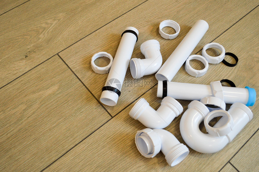 白色塑料管道管道光滑和弯曲配件法兰橡胶垫圈在米色板的背景下图片