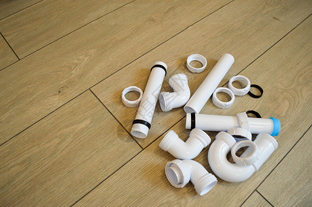 白色塑料管道管道光滑和弯曲配件法兰橡胶垫圈在米色板的背景下图片