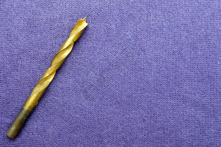 黄色铜钻木头的紫布背景钻探图片