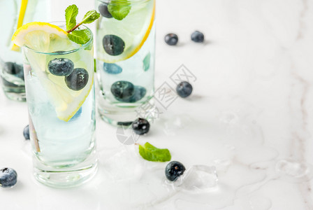 夏季茶点饮料蓝莓柠檬水或莫吉托鸡尾酒加柠檬新鲜蓝莓和薄荷白色大理石图片