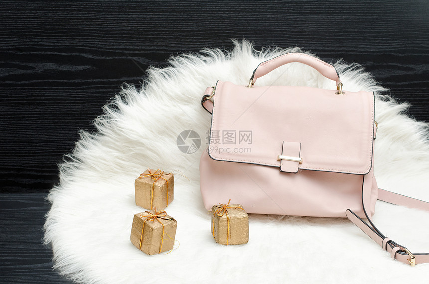 白色毛皮黑色桌子上的粉色袋子和礼品盒时尚理念图片