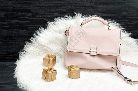 白色毛皮黑色桌子上的粉色袋子和礼品盒时尚理念图片