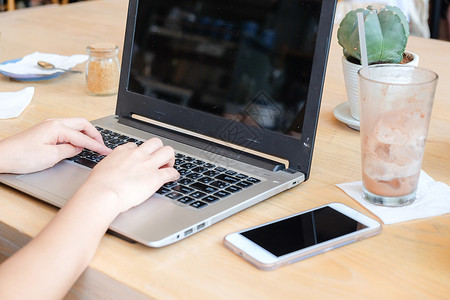 年轻商业女在咖啡店使用笔记本电脑和手机商业图片