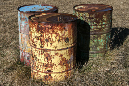 旧生锈的废弃垃圾燃料桶在彩弹干草场操中间图片