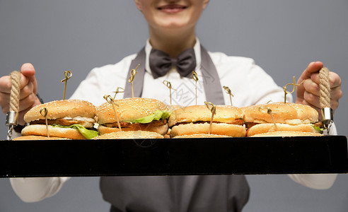 服务员手上拿着一个装汉堡的托盘图片