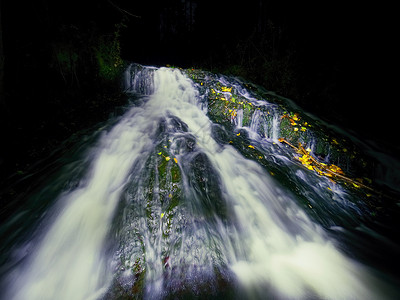 白水喷在溪流上的瀑布中图片