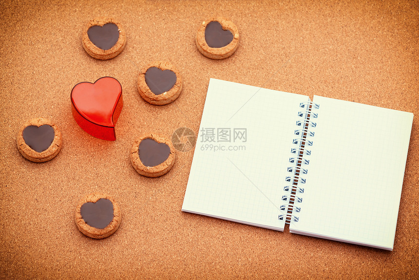 日背景有饼干红心和用笔记本在木图片