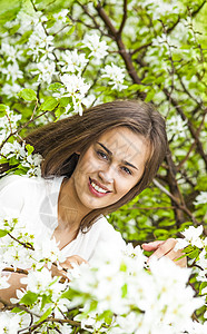 美丽的天然棕色褐发女人的肖像在鲜花苹果树开花图片