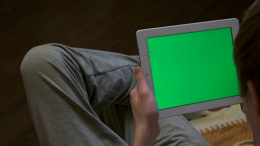 模糊的人拿着带有空白可编辑绿屏的平板电脑的后视图男子手持平板电脑与图片
