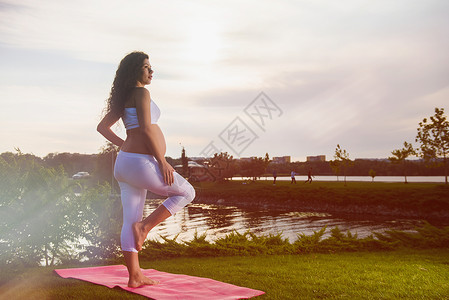 美丽的年轻孕妇做瑜伽在Vrksasana运动中图片
